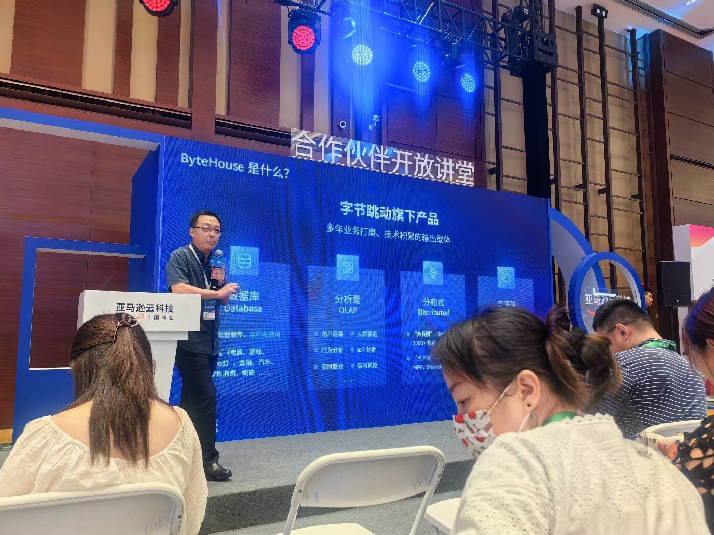 Picture of a Chinese man speaking on stage against a blue backdrop