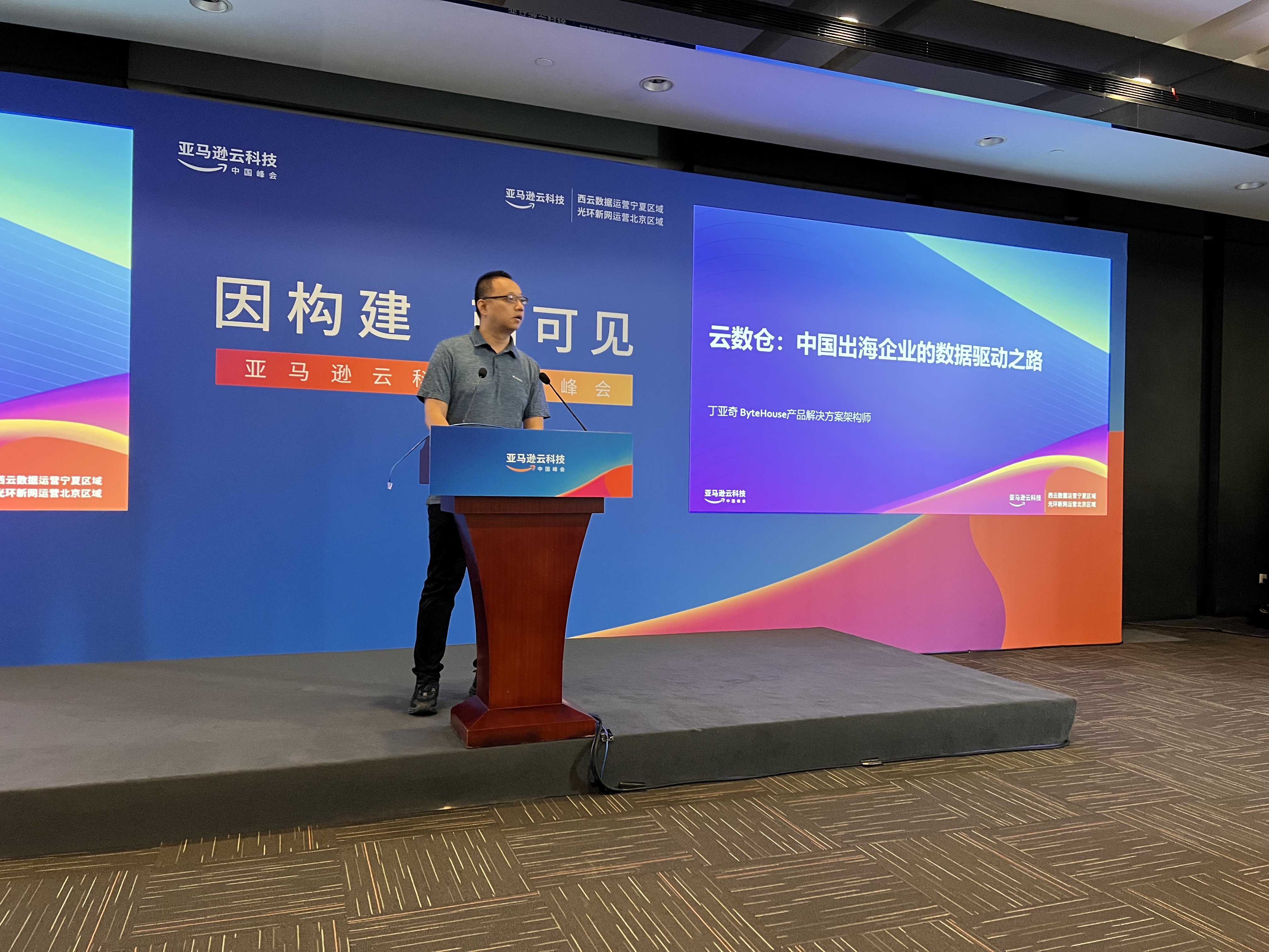 A Chinese man standing and speaking behind a podium