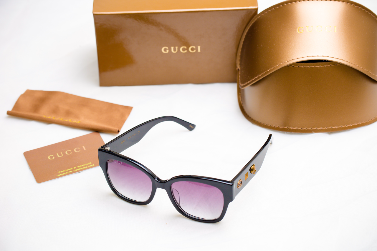 Black Gucci sunglasses out of its bronze casing 
