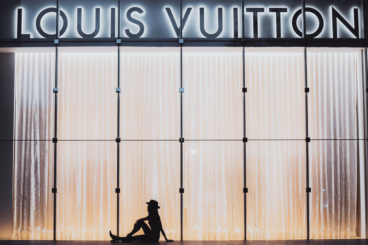 Silhouette of a woman seated in front of a Louis Vuitton department storefront